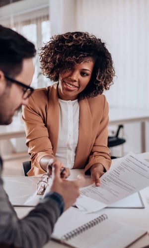 Couple sitting at the desk in the bank and signing loan agreement