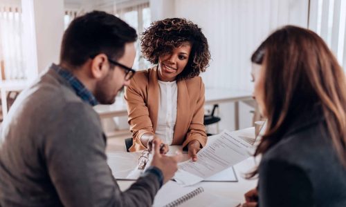 Couple sitting at the desk in the bank and signing loan agreement