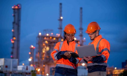 employees working together with computer wearing safety gear